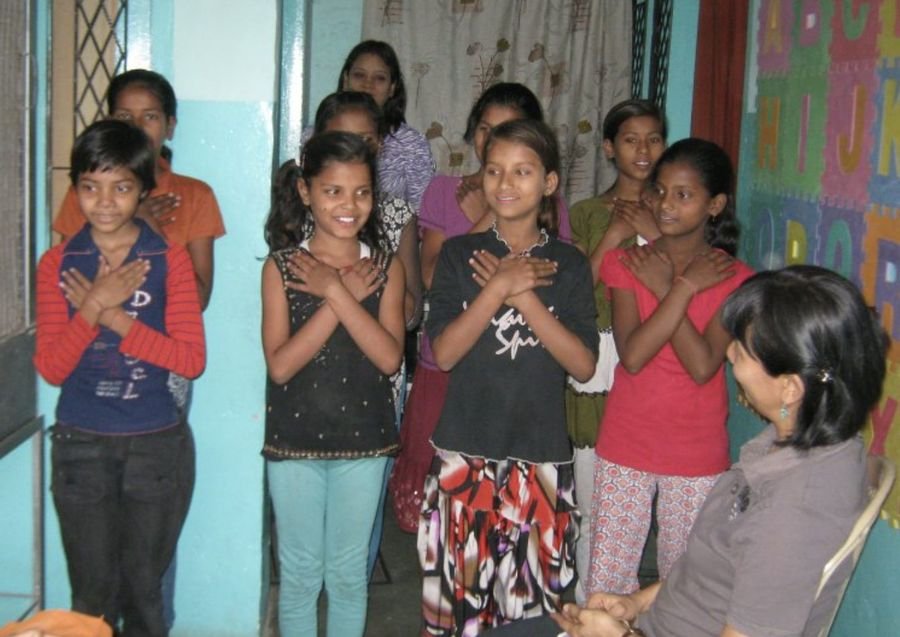 Girls at a community centre standing with hands crossed over their hearts